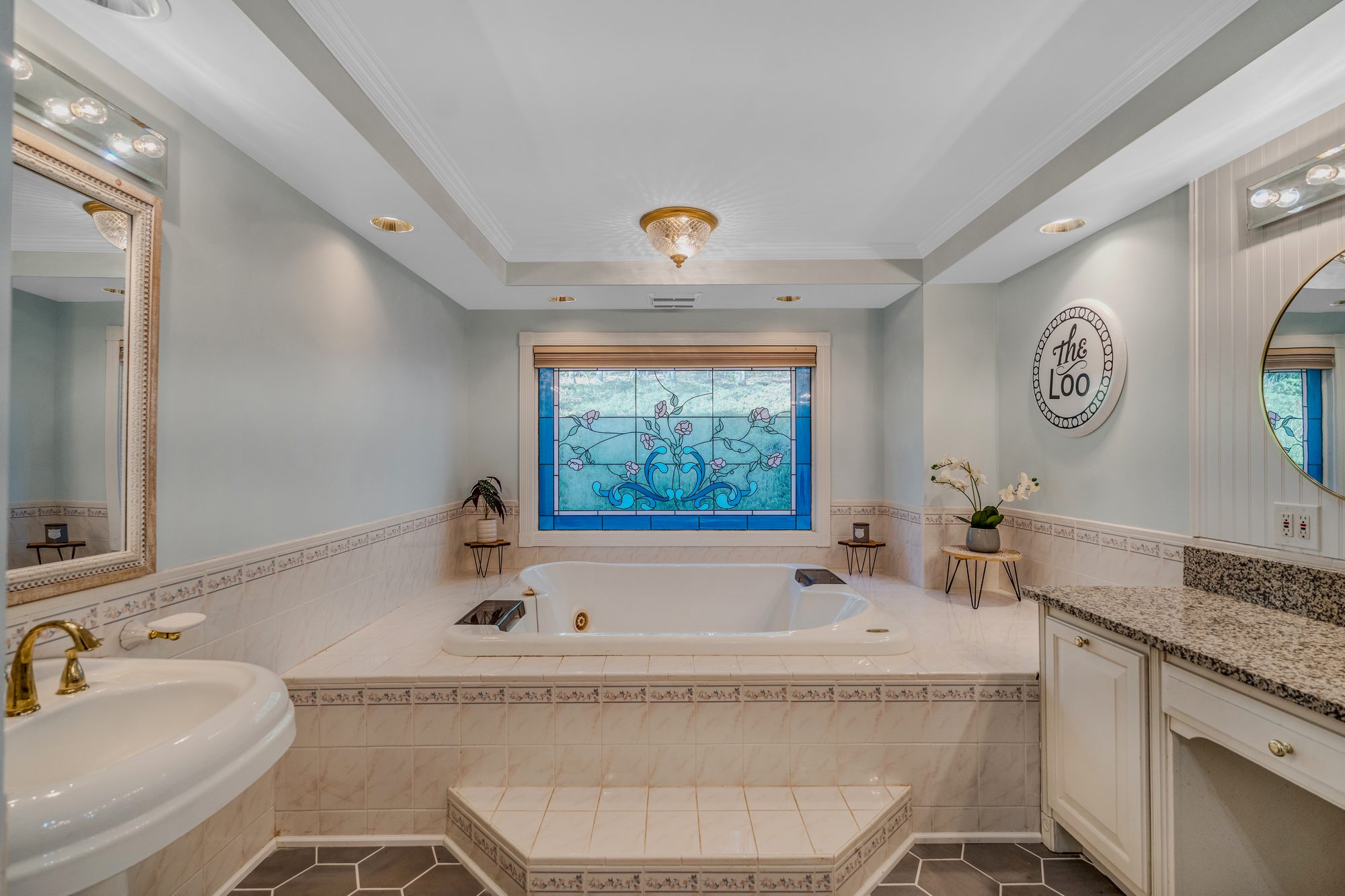 The primary bath, jetted tub beneath the original stained glass window